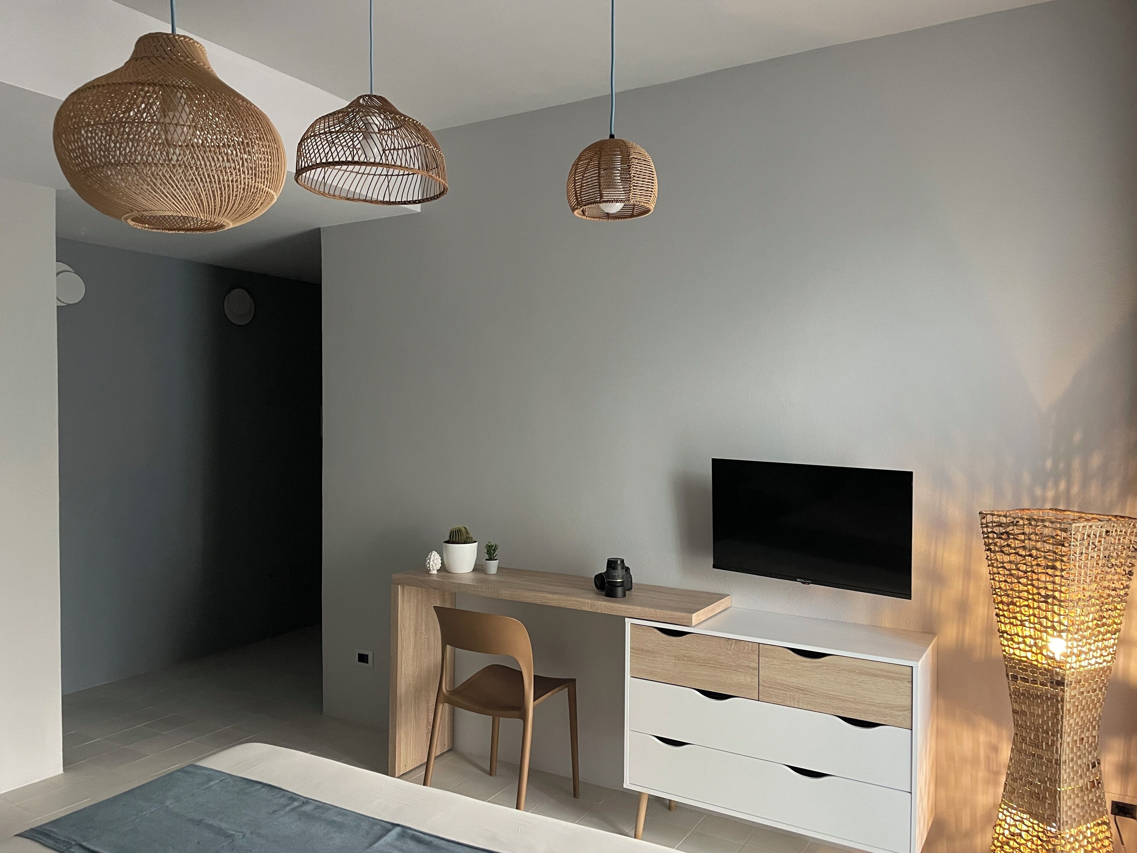 Ein modernes Schlafzimmer mit einem Holztisch, einem Fernseher und zwei hängenden Korbtischen.