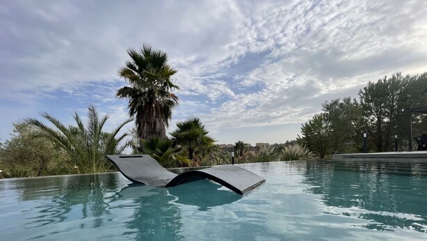 An infinity pool with a clear view of the sky and palm trees in the background.