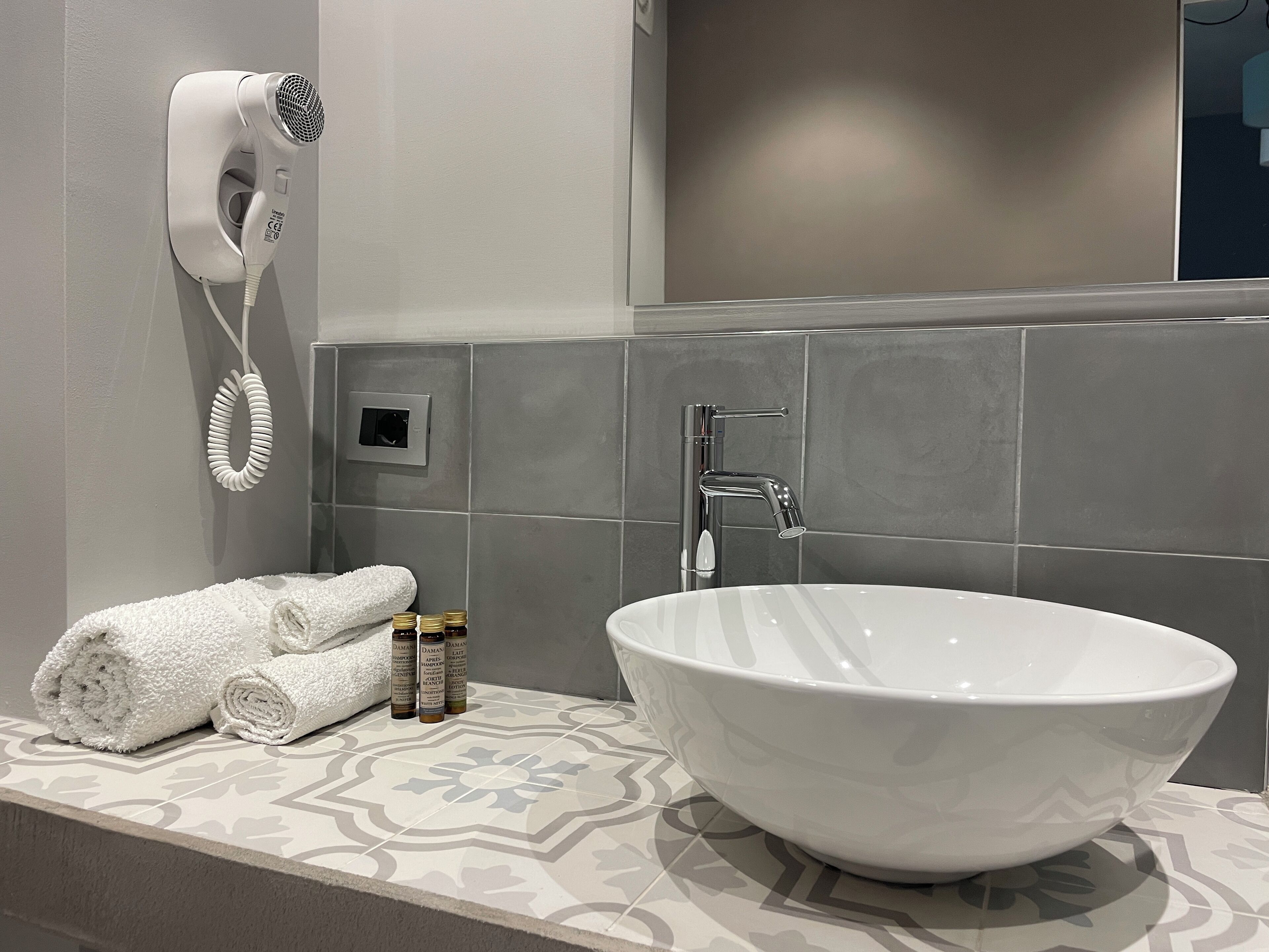 Une salle de bain avec un lavabo blanc, un sèche-serviettes et des articles de toilette posés sur le comptoir.