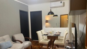 Una sala de estar con un sofá, sillas, una mesa de comedor con vasos y platos, un televisor y una chimenea.