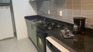 Una cocina con estufa a gas, microondas y cafetera.