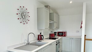 A modern kitchen with a sink, stove, microwave, and kettle. - Beech Cottage - UK49211 (near Okehampton)
