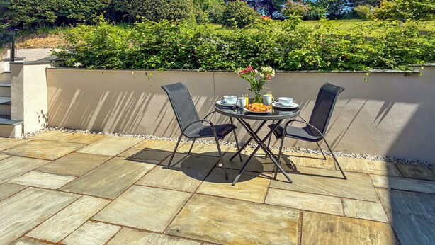 An outdoor patio with stone flooring, a table set for two, and chairs. - Beech Cottage - UK49211 (near Okehampton)