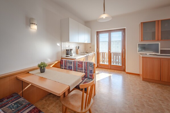 Eine kompakte Küche mit Essbereich, einem kleinen Fernseher und einem Balkon mit Blick.
