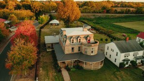 A large, multi-story stone house with a circular tower, surrounded by a well-maintained lawn and trees. - Bonaparte Castle (Salisbury)