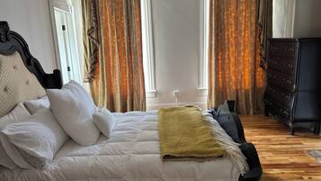 A bedroom with a bed, a dresser, and a window with curtains.