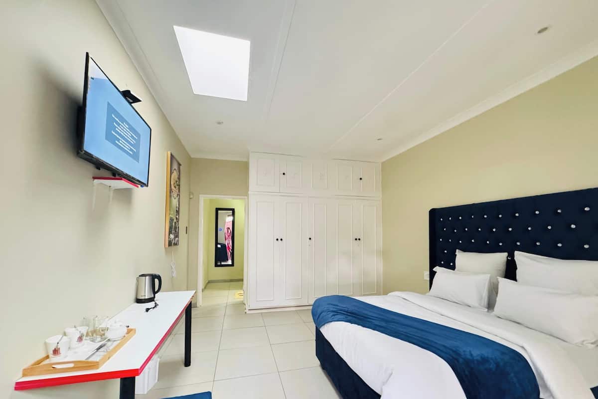 Ein Hotelzimmer mit Bett, Schreibtisch, einer Ablage mit Gegenständen, Fernseher und Kleiderschrank.