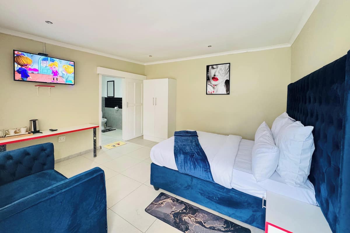 Ein Hotelzimmer mit Bett, Fernseher, Schreibtisch und Stuhl.