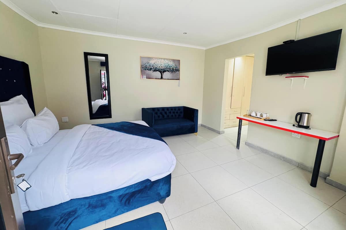 Ein Hotelzimmer mit Bett, einer Sitzecke, einem Fernseher und einem kleinen Tisch mit Wasserkocher.