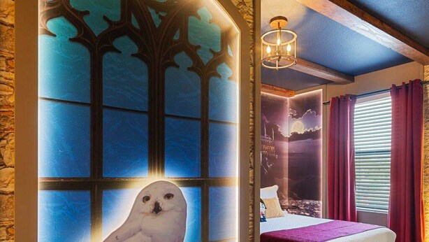 A bedroom with a stone wall, a bed with a purple bedspread, and a wall-mounted owl artwork. - The Hub 3b Close to Disney Gameroom (Kissimmee)