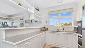 A modern kitchen with white cabinetry, a granite countertop, and a window with a view of trees. - Kookaburras Perch - McCrae (McCrae)