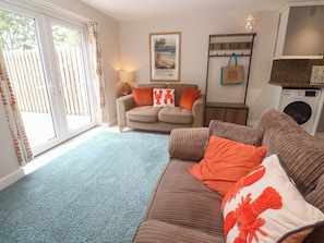 A living room with a sofa, a coffee table, a lamp, and a framed picture on the wall. - The Packing House (Penzance)