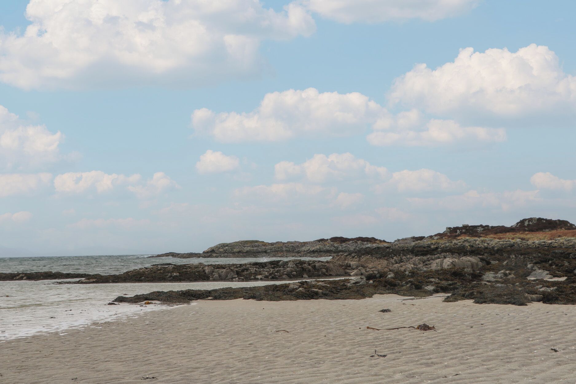 Ein Strand mit felsiger Küste und blauem Himmel.