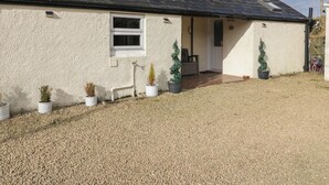 Ein eingeschossiges Haus mit Schotterauffahrt, einer kleinen Veranda und Blumentöpfen.