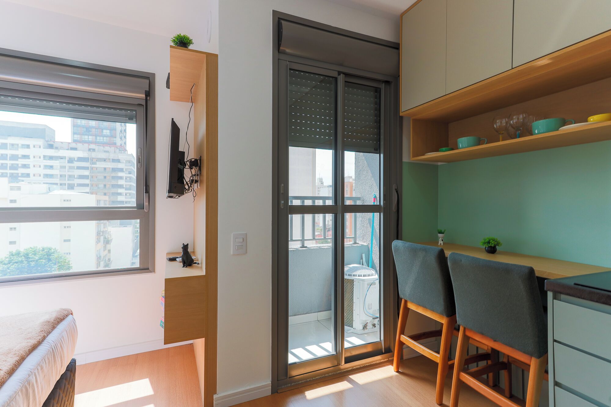 A modern apartment with a balcony, a kitchen area with wooden cabinets, and a dining area with two chairs.