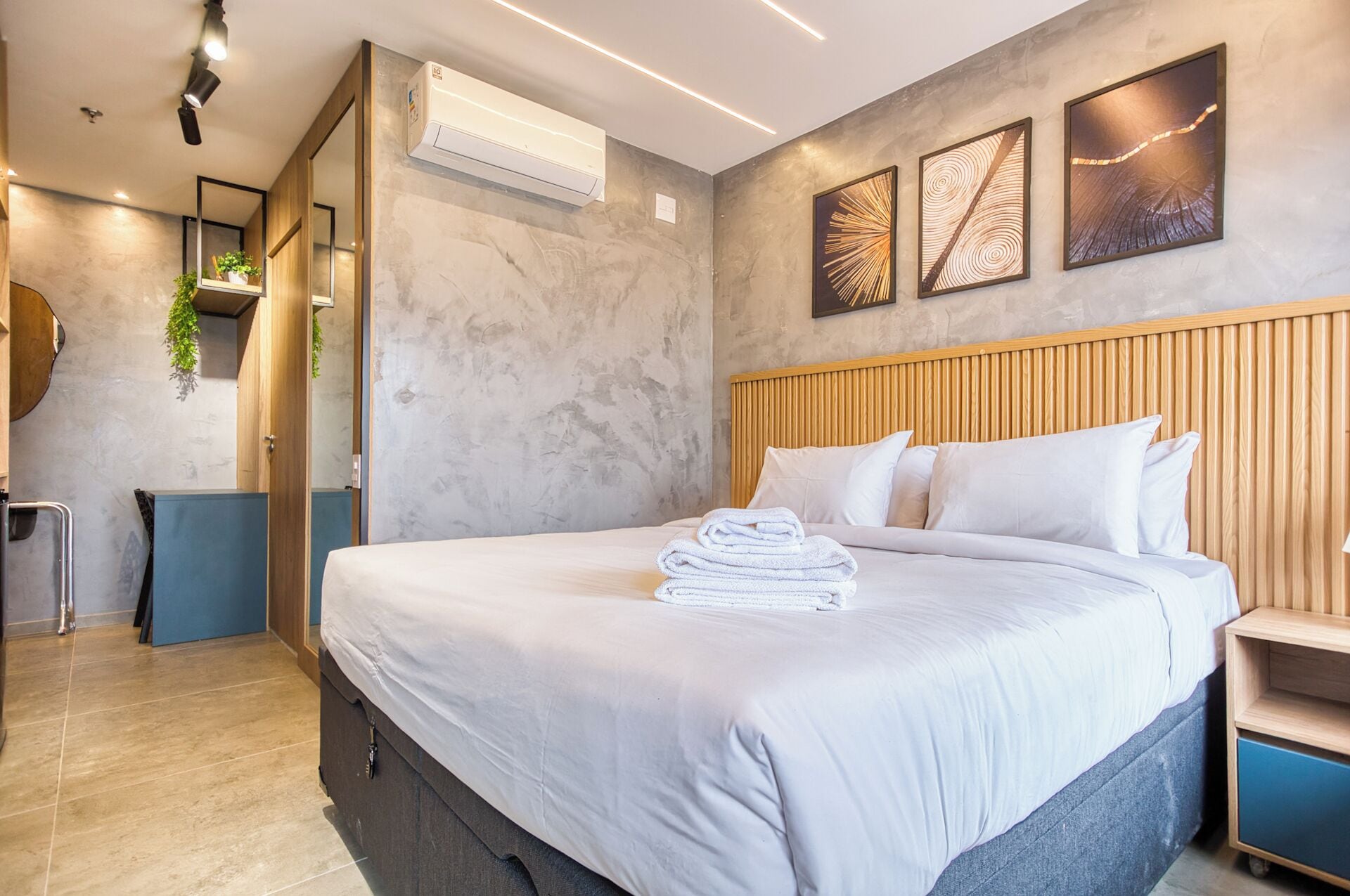 Una habitación de hotel moderna con una cama grande, cabecera de madera y aire acondicionado de pared.