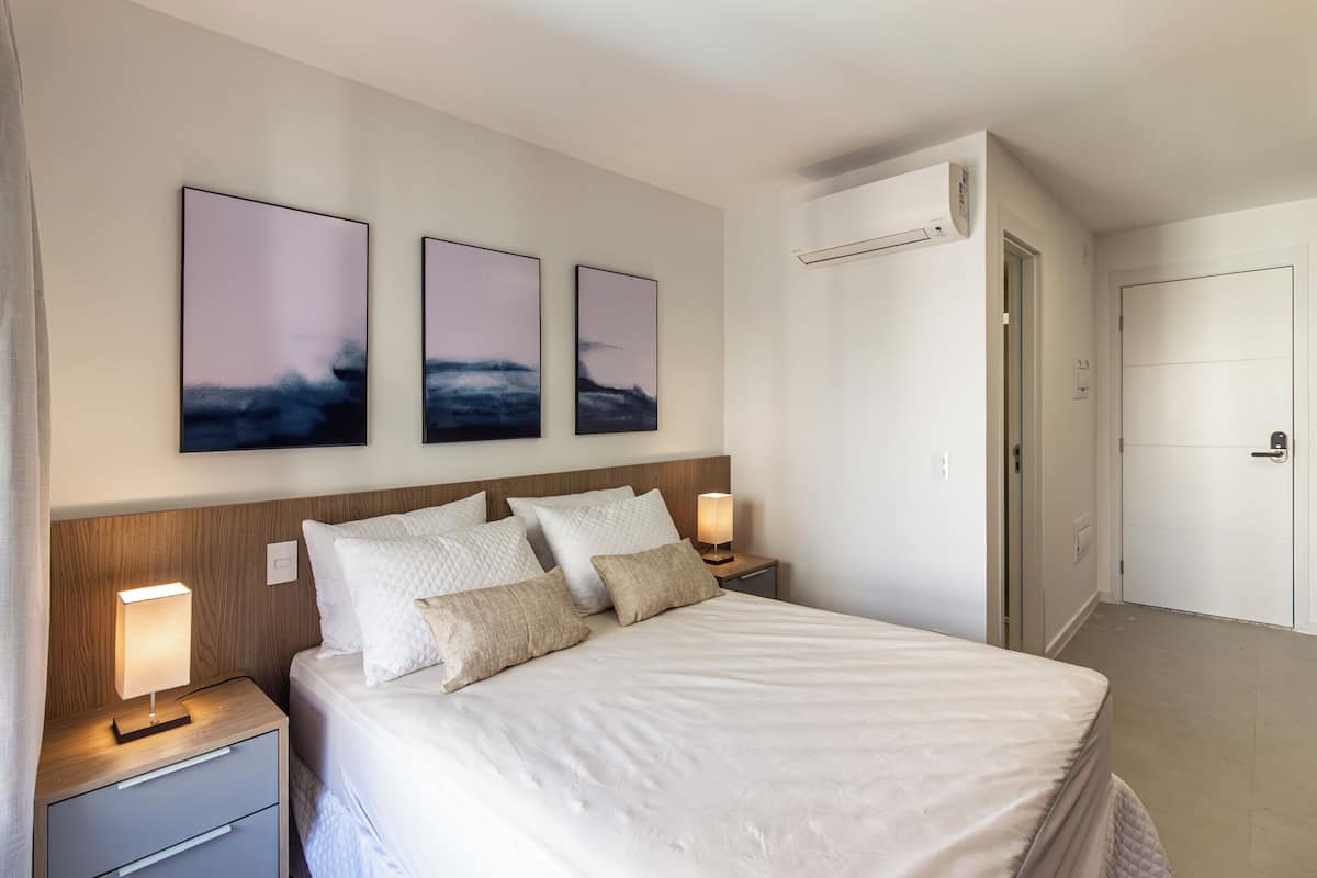 A neatly arranged bedroom with a bed, bedside tables, and wall-mounted air conditioning unit.