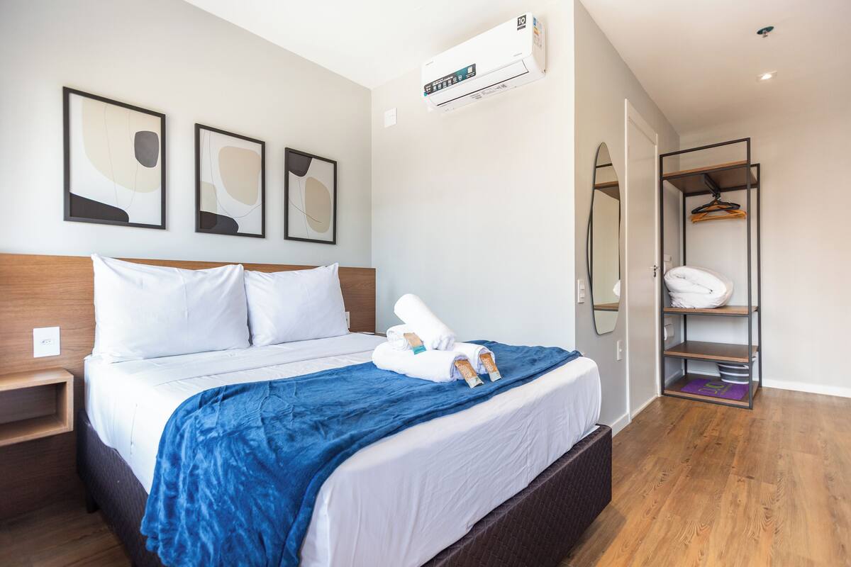 A hotel room with a bed, a wardrobe, and a mirror.
