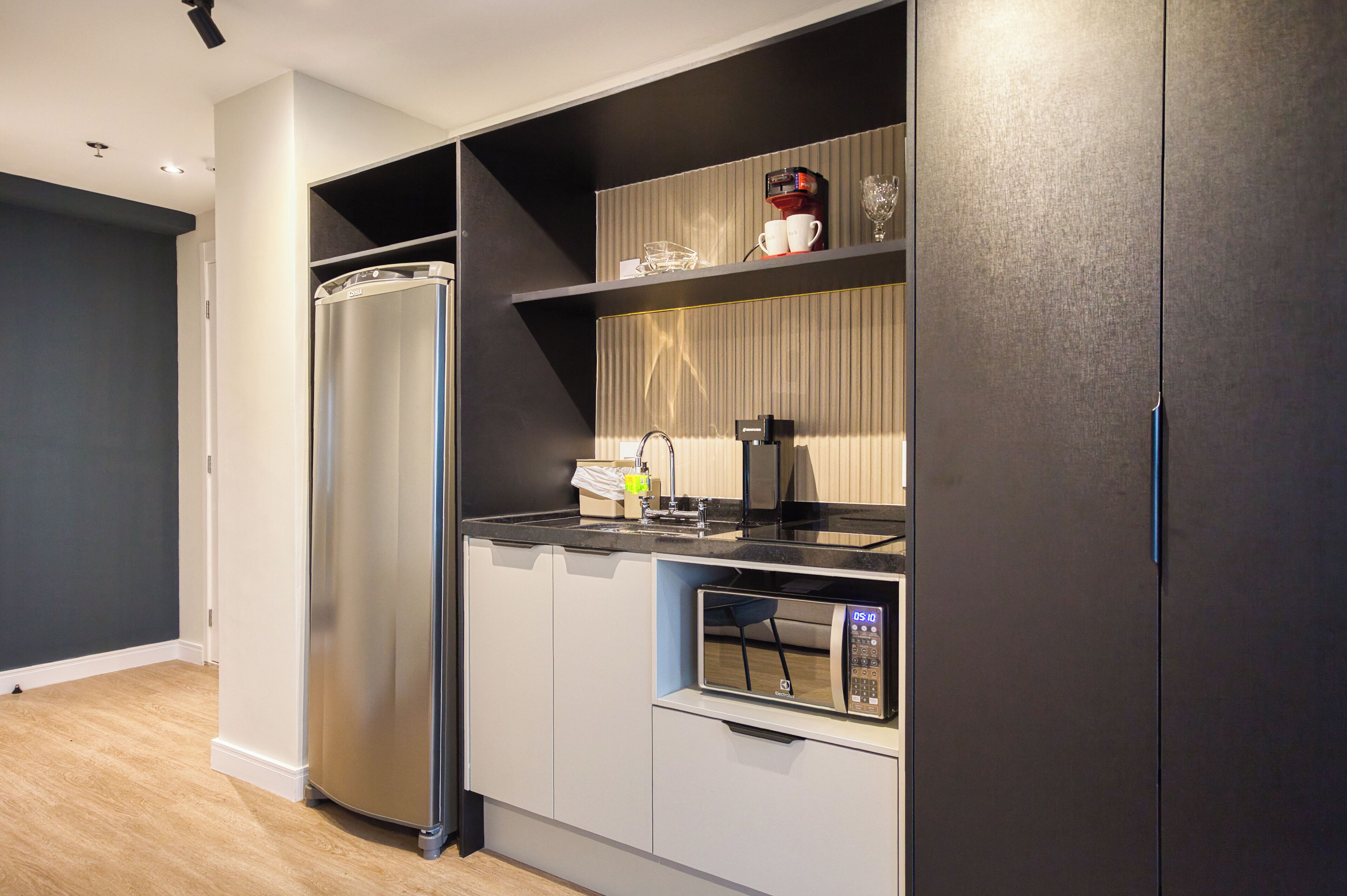 Una cocina moderna con refrigerador, microondas y cafetera integrados.