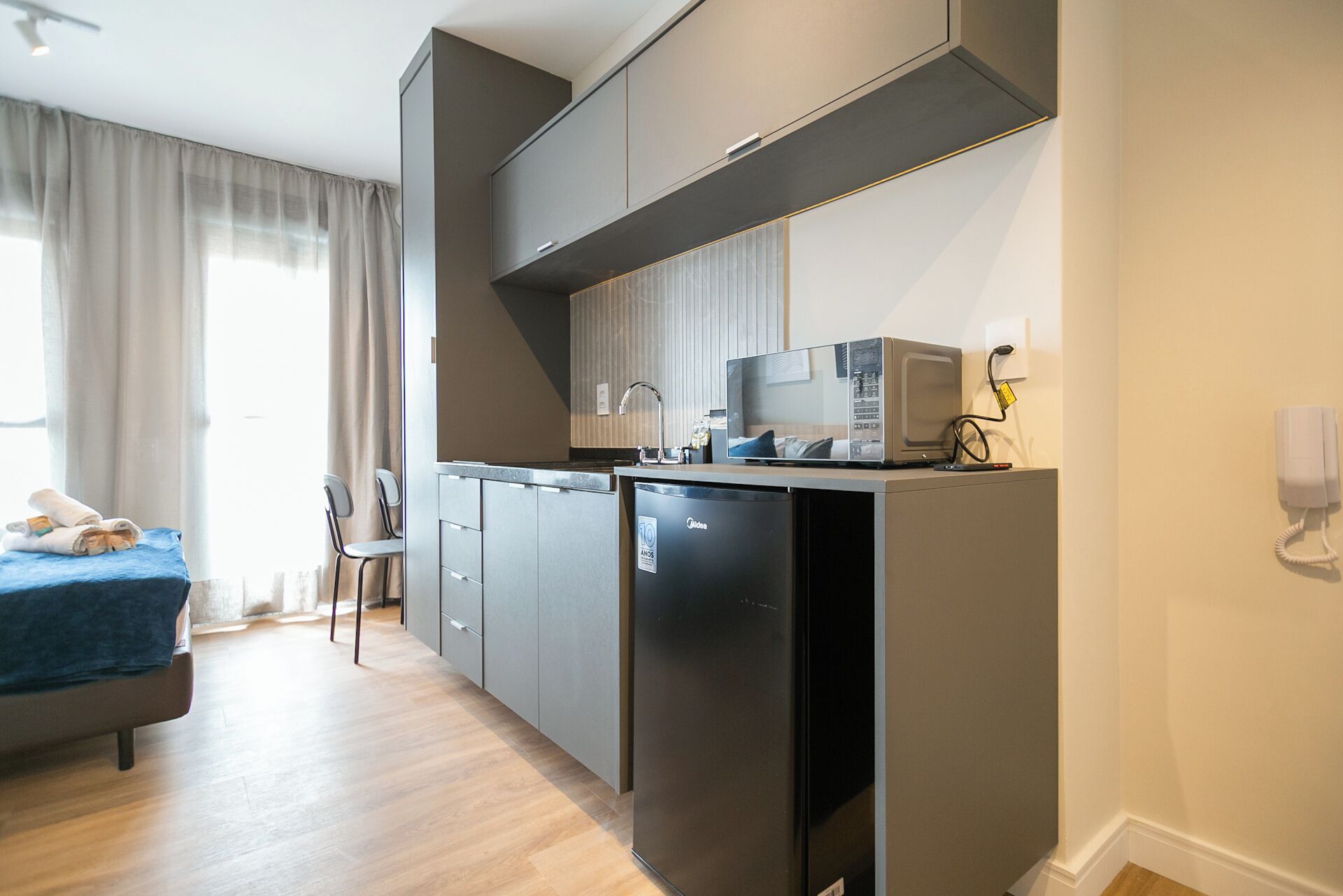 Une chambre d’hôtel compacte comprenant un coin cuisine, un lit et un espace salon.