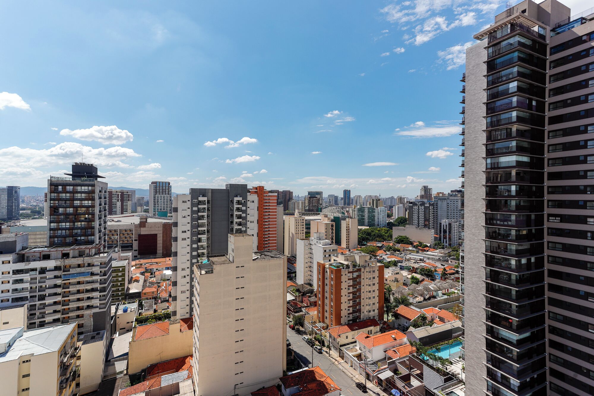 A high-rise building with multiple floors, surrounded by other buildings and a clear sky.