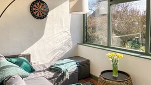 A cozy room with a bed, a dartboard, a window with a view, and a small table with flowers. - 3 bedroom accommodation in Monyash, near Bakewell (Monyash, near Bakewell)