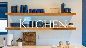 Een keuken met twee houten planken, een aanrecht en een wandplank met keukengerei.