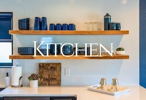 Een keuken met twee houten planken, een aanrecht en een wandplank met keukengerei.