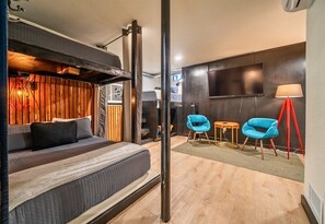 Un dormitorio moderno con una litera, un televisor de pantalla plana y dos sillas azules.