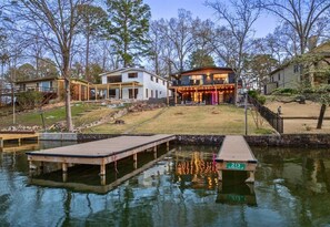 Una propiedad junto al lago con muelle, una casa con porche cubierto y un bote pequeño.