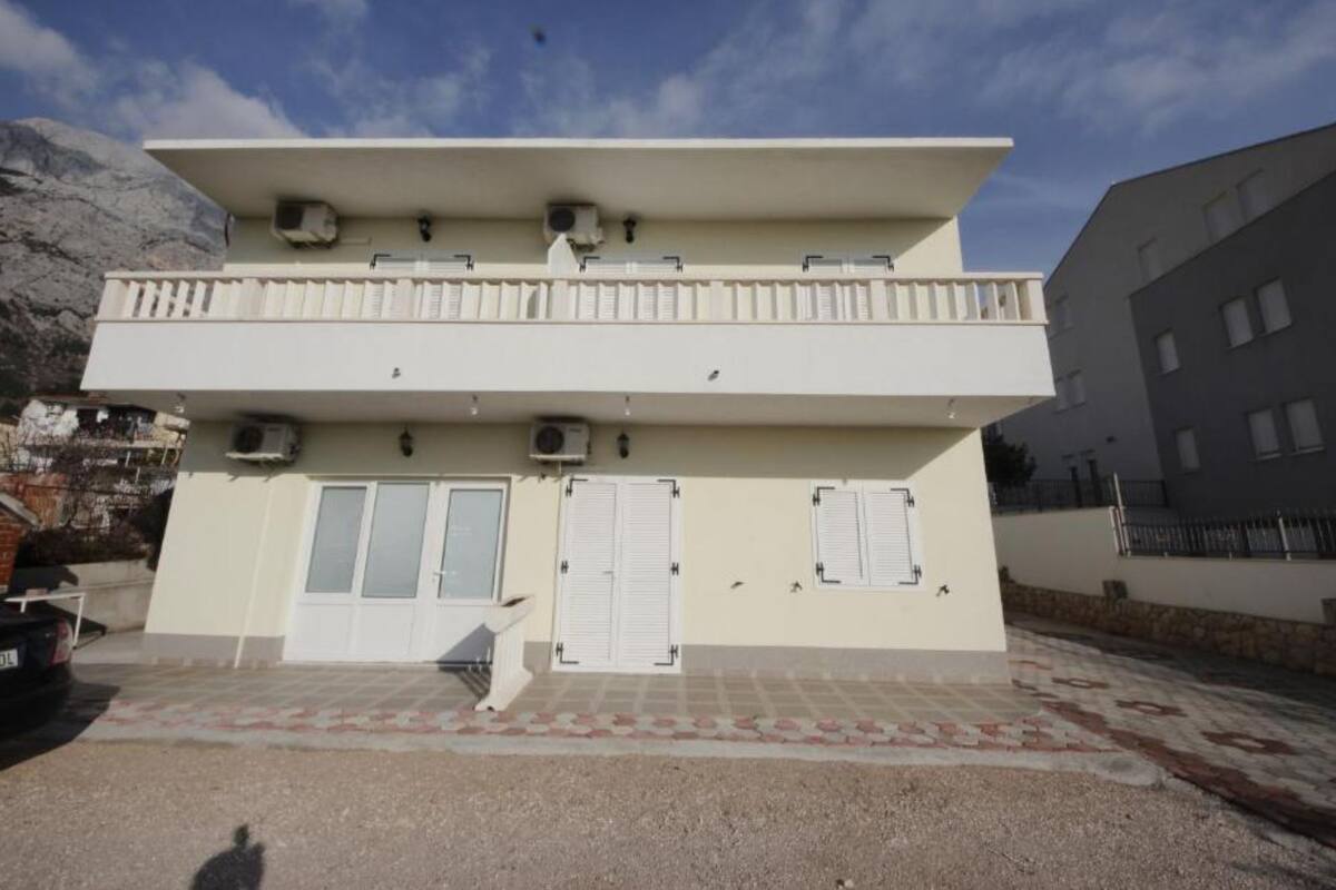 A two-story building with a flat roof, air conditioning units, and a balcony.