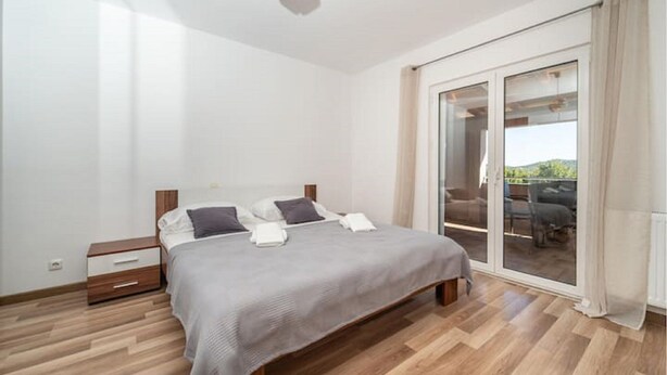 Una camera da letto con un letto, comodini e una porta scorrevole in vetro che dà su uno spazio esterno.