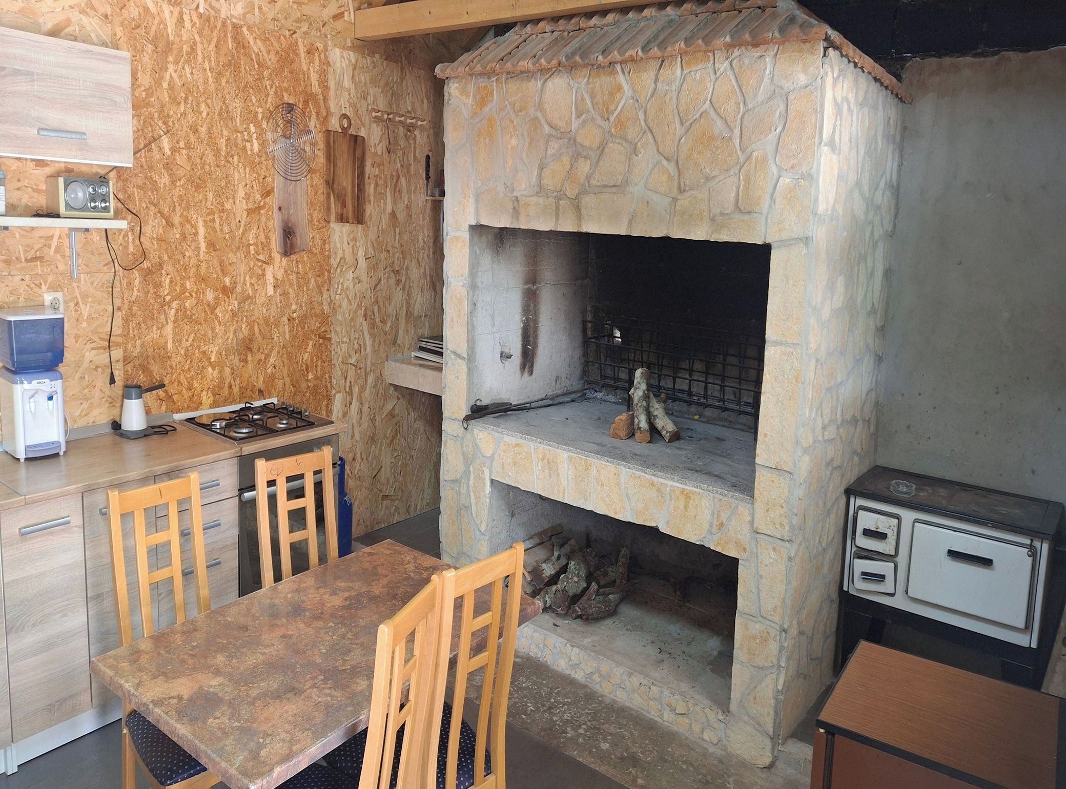 Une cuisine rustique avec un four en pierre, des armoires en bois et une table à manger avec des chaises.
