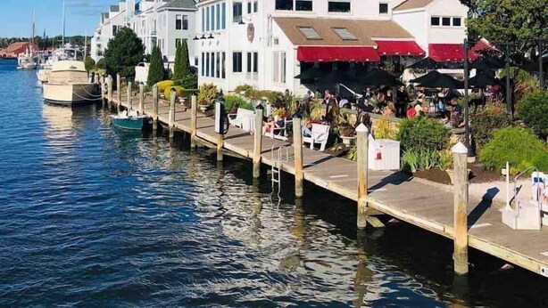 A waterfront hotel with a dock extending into the water, featuring multiple dining areas with outdoor seating. - Charming Walk to downtown Mystic Awaits Your Stay (Mystic)