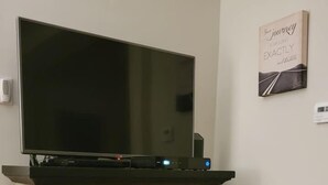 A stone fireplace with a TV on top and a fire burning inside.