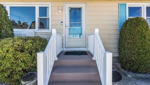 A house with a front porch, a door with a glass panel, and a small step leading up to the entrance. - Professionally Managed | Walk to Beach (Seaside Heights)