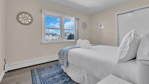 A bedroom with a bed, a window, a ceiling light, and a door. - Professionally Managed | Walk to Beach (Seaside Heights)