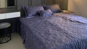Een moderne slaapkamer met een groot bed, een nachtkastje, een spiegel en een wandlamp.