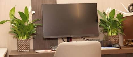 Un escritorio moderno con un monitor de pantalla plana, dos macetas y una silla.