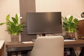 A modern office desk with a flat-screen monitor, two potted plants, and a chair. - Lishan Yizhai Inn (Xi'an)
