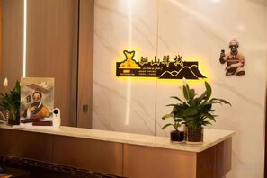 A reception desk with a marble wall, a neon sign, and a statue. - Lishan Yizhai Inn (Xi'an)