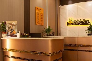 A hotel reception desk with a wooden finish, a framed welcome sign, and a potted plant. - Lishan Yizhai Inn (Xi'an)