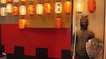 Una habitación con una pared roja, una estatua y faroles colgantes.