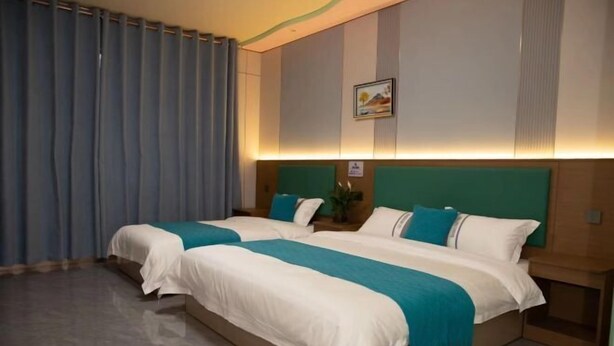 A hotel room with two beds, a nightstand, and a wall-mounted picture. - Lishan Yizhai Inn (Xi'an)