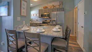 A kitchen with granite countertops, stainless steel appliances, and a dining area with four chairs. - Stylish 2BR Coastal Getaway w/ Pool & Prime Location Lazy Fun (Port Aransas)