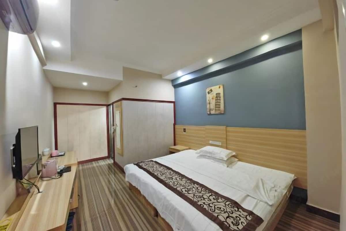 Habitación de hotel con cama, escritorio, televisor y un cuadro en la pared.