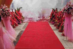 Un tapis rouge menant à une allée bordée de chaque côté de décorations florales.