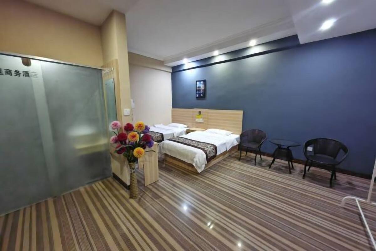 Habitación de hotel con una cama, un escritorio y una silla. Hay un florero con flores sobre el escritorio.