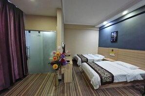 Une chambre d’hôtel avec deux lits, un bureau agrémenté d’un vase de fleurs, un miroir et une porte.