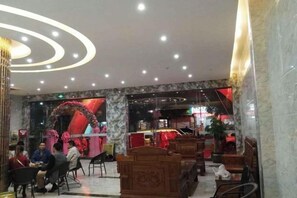 Un hall d’hôtel avec un sol en marbre, des espaces aménagés avec des sièges et un comptoir d’accueil.